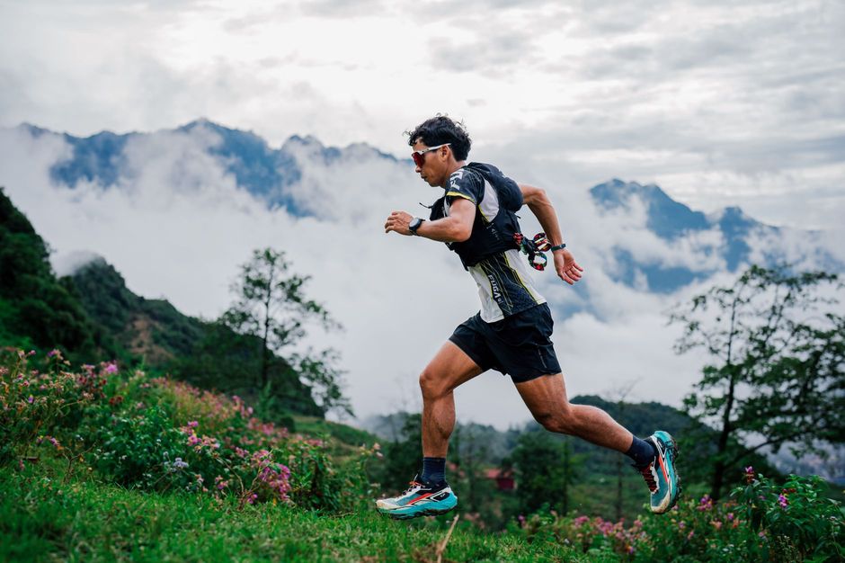 A trail runner sprinting across a misty mountain ridge