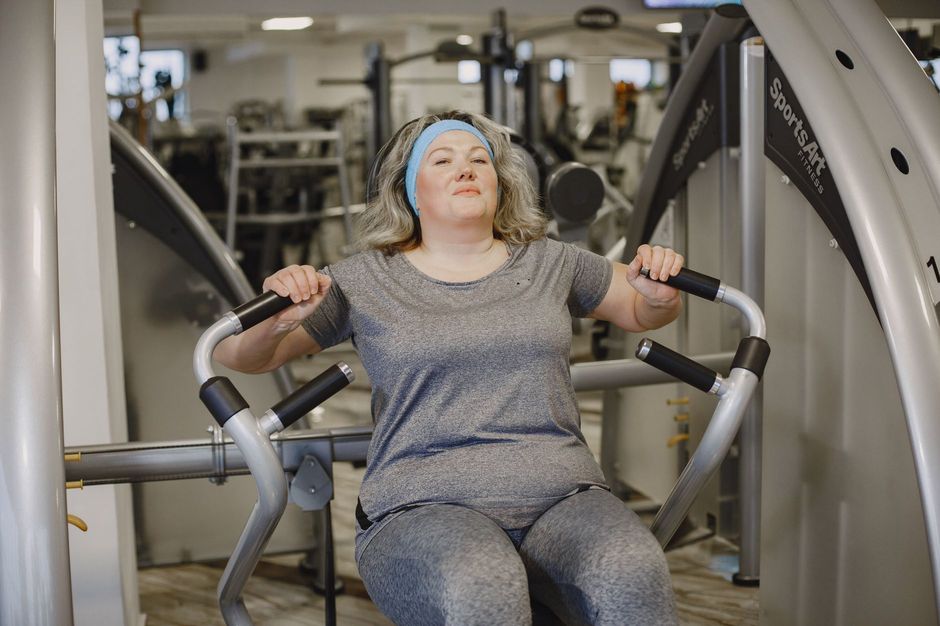 A middle-aged woman doing strength training on a gym machine